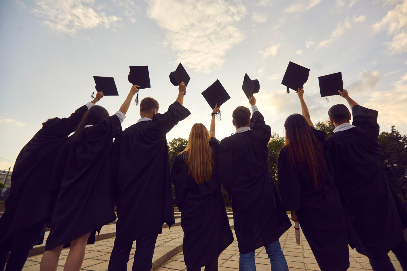 Back View of Group of University Graduates Holding Academic Caps before Throwing Them in Air